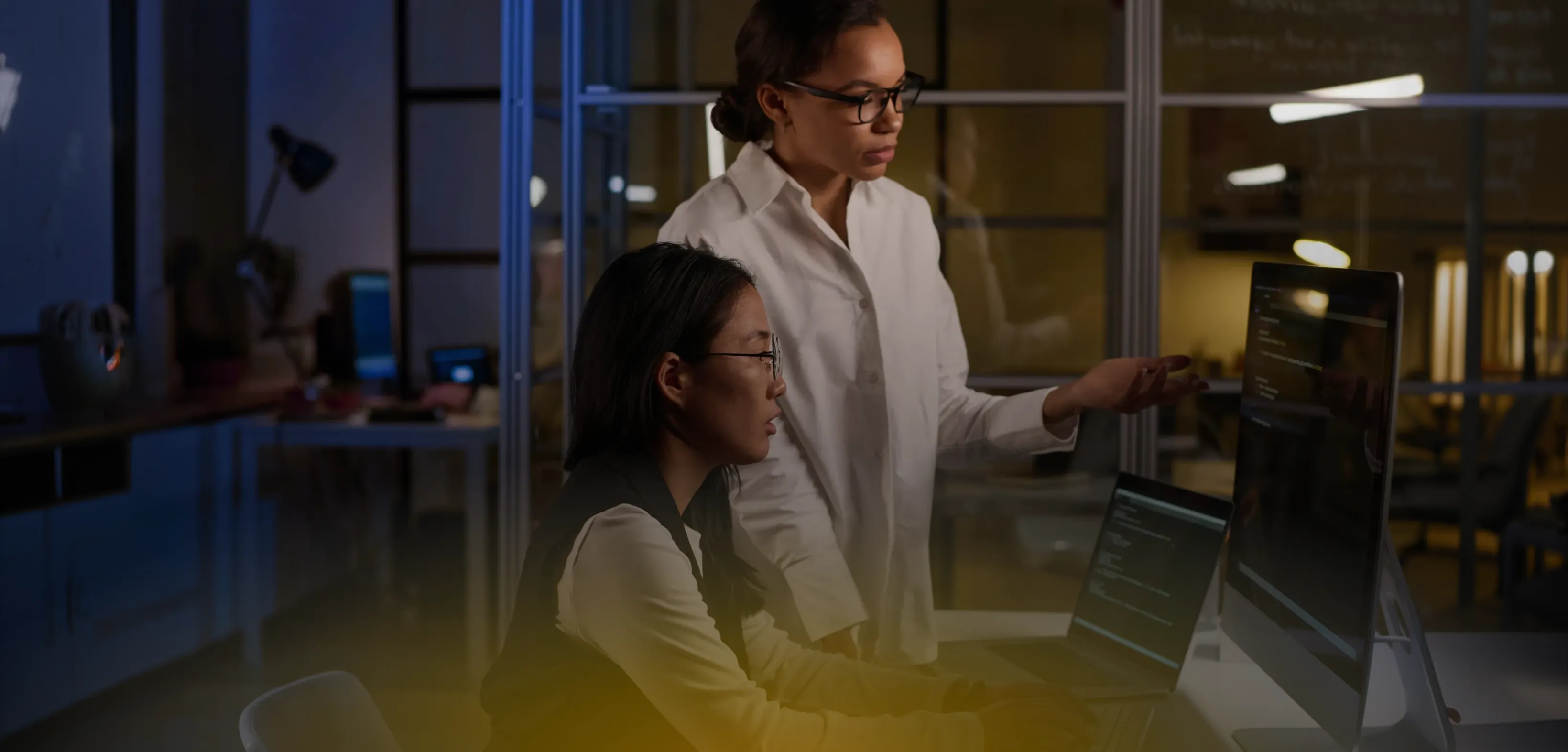 Technology team collaborating at a workstation in a dimly lit office at night